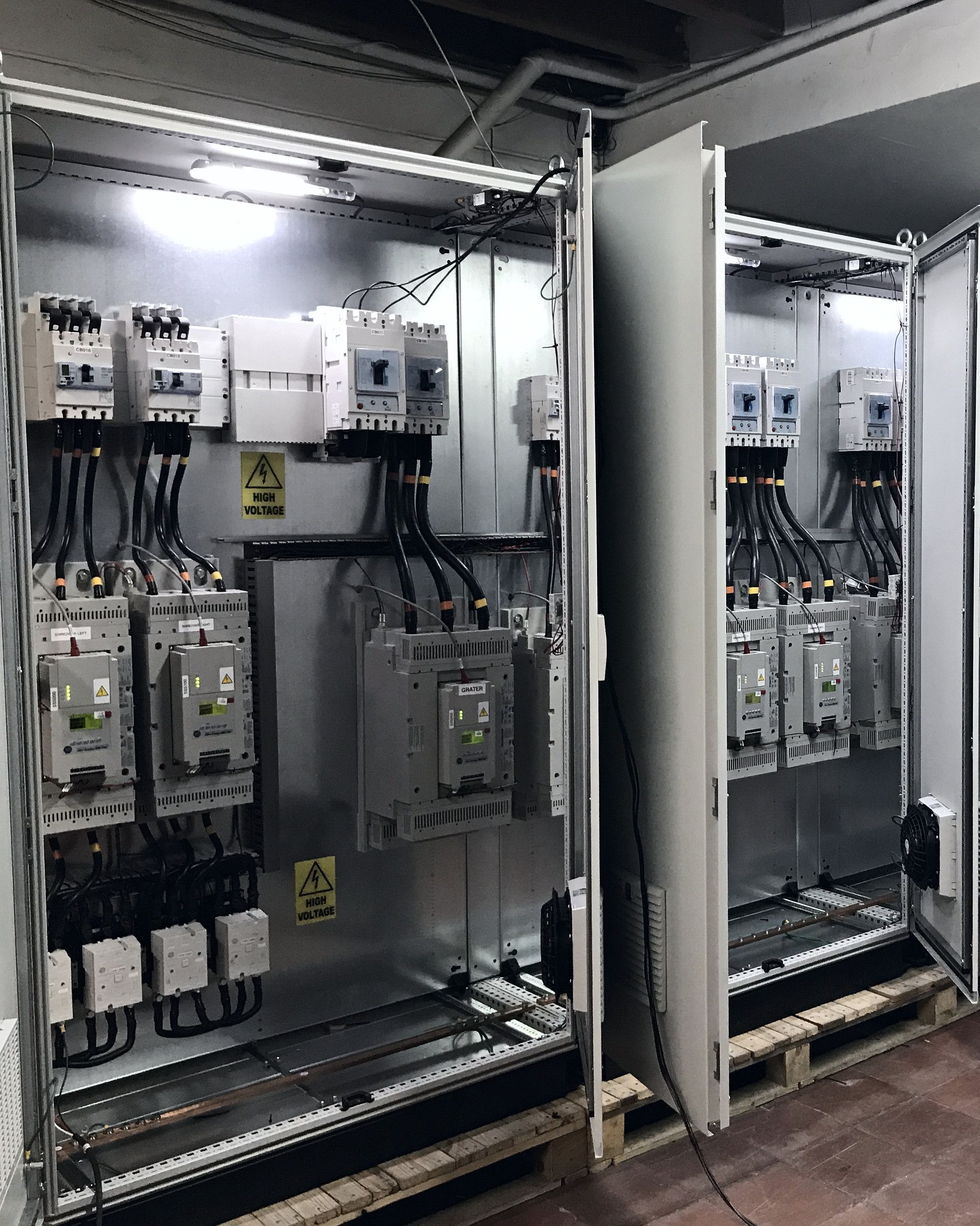 Tableros de varias secciones abiertos, con contactores, variadores y rack de PLC.