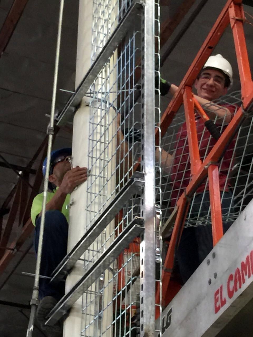 Técnicos sobre una plataforma elevadora instalando un tramo vertical de bandeja portacables.