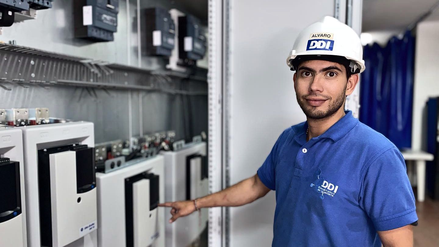 Técnico de DDI junto a variadores de velocidad Allen-Bradley PowerFlex en un tablero.